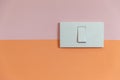 Close up of white Light Switch with copy space on pink and orange wall. Royalty Free Stock Photo