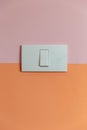 Close up of white Light Switch with copy space on pink and orange wall. Royalty Free Stock Photo
