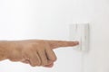 Close-up light switch of a male finger will turn on or off a light switch with white wall at home. white plastic mechanical switch Royalty Free Stock Photo