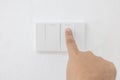 Close-up light switch of a male finger will turn on or off a light switch with white wall at home. white plastic mechanical switch Royalty Free Stock Photo