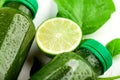 Close up of the lime slice lying between the bottles of green beverage on white backfround. The concept of creating a refreshing