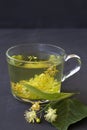 Linden flowers tea.Cup of hot herbal tea with linden fresh flowers on a black table Royalty Free Stock Photo