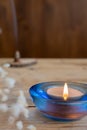 Close-up of lit candle with blue glass, incense and white flowers, selective focus, on wooden table Royalty Free Stock Photo