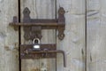 Close-up of lit by sun old rough made of wooden planks house door or barn gate with iron rusty slide bolt lock. Outdated Royalty Free Stock Photo