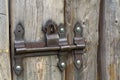 Close-up of lit by sun old rough made of wooden planks house door or barn gate with iron rusty slide bolt lock. Outdated Royalty Free Stock Photo