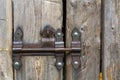 Close-up of lit by sun old rough made of wooden planks house door or barn gate with iron rusty slide bolt lock. Outdated technolog Royalty Free Stock Photo