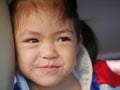 Close up of a little Asian baby girl face smiling, being in a good mood, and leaning on the seat of a car - facial expression of Royalty Free Stock Photo