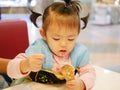 Close up of little Asian baby girl scooping ice cream Royalty Free Stock Photo