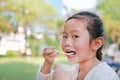 Close-up little Asian child girl eating yogurt in park Royalty Free Stock Photo