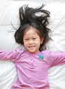 Close-up little Asian child girl lying on bed looking at camera. Above view Royalty Free Stock Photo