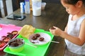 Close up little Asian kid girl in process class of homemade chocolate donuts Royalty Free Stock Photo