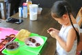 Close up little Asian kid girl in process class of homemade chocolate donuts Royalty Free Stock Photo