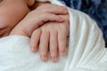 Close-up of little baby handles. The sleeping Newborn boy under a white knitted blanket lies on the blue fur. Royalty Free Stock Photo