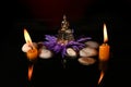 a little Buddha statue sitting on a lotus flower with candles Royalty Free Stock Photo