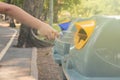 Close up little child hand putting used plastic bottle in public recycle bins or segregated waste bins in public park.