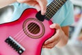 Close-up little cute blond girl having fun learning to play small ukulele guitar at home.Toddler girl trying to play toy musical i Royalty Free Stock Photo