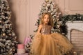 Close up. Little girl in a golden dress jumps and has fun in the decorated room waiting for Christmas Royalty Free Stock Photo