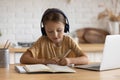 Close up little girl in headphones taking notes studying online Royalty Free Stock Photo