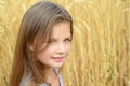 Close-up little girl with long hair green eyes in golden rye field summer day. Concept of purity, growth, happiness Royalty Free Stock Photo