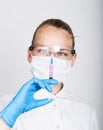 Close-up little girl in a medical dress and gloves holding a syringe Royalty Free Stock Photo