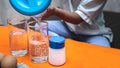 Close up the little girl is pouring water into a clear glass, to conduct a science experiment on eggs and salt. Royalty Free Stock Photo