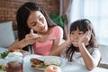 Close up of asian little girl refuses to eat when her older sister feed her food with a spoon by seducing Royalty Free Stock Photo