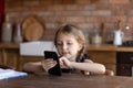 Close up little girl using phone at home, browsing apps