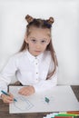 Close up of little girl in white blouse which is focused on drawing. Preschooler is learning how to draw. Kindergarten and school.