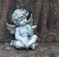 Cemetery scene. Close up of a sad pensive angel sitting on a grave. Pain, fear, end of life Royalty Free Stock Photo