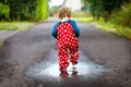 Close-up of little toddler girl wearing rain boots and trousers and walking during sleet, rain on cold day. Baby child Royalty Free Stock Photo