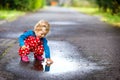 Close-up of little toddler girl wearing rain boots and trousers and walking during sleet, rain on cold day. Baby child Royalty Free Stock Photo