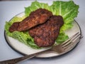 Close-up of liver cutlets and leaf salad for a hearty diet breakfast on a white background