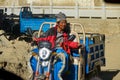 CLOSE UP: Local Tibetan man rides his motorcycle tricycle through a village.