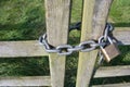 Close up of locked chain around a closed wooden gate