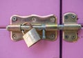 Close up with a locked purple door. Door latch with a rusty golden lock