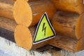 Close-up of log house. Corner of old wooden house with yellow metal sign with image of lightning bolt attached to it Royalty Free Stock Photo