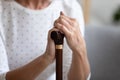 Close up lonely older woman holding hands on walking stick