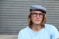 Close up of long haired blond male wearing glasses and news paper boy hat with copy space on the left Royalty Free Stock Photo