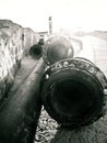 Close up of long pipes lying down on the ground near a wall in Tel Aviv port, in black and white