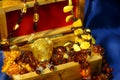 Close-up a lot of jewelry from amber in wooden chest on a blue background. Royalty Free Stock Photo