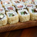 Close-up of a lot of sushi rolls with different fillings lie on a wooden surface. Macro shot of cooked classic Japanese food with Royalty Free Stock Photo