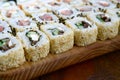 Close-up of a lot of sushi rolls with different fillings lie on a wooden surface. Macro shot of cooked classic Japanese food with Royalty Free Stock Photo