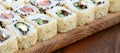 Close-up of a lot of sushi rolls with different fillings lie on a wooden surface. Macro shot of cooked classic Japanese food with Royalty Free Stock Photo