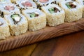 Close-up of a lot of sushi rolls with different fillings lie on a wooden surface. Macro shot of cooked classic Japanese food with Royalty Free Stock Photo