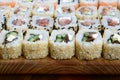 Close-up of a lot of sushi rolls with different fillings lie on a wooden surface. Macro shot of cooked classic Japanese food with Royalty Free Stock Photo