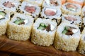 Close-up of a lot of sushi rolls with different fillings lie on a wooden surface. Macro shot of cooked classic Japanese food with Royalty Free Stock Photo