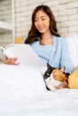 Close up lovely multicolor cat lie on bed near owner who reading some books and pillow also it look relax stay in bedroom with Royalty Free Stock Photo