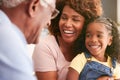 Close up Of Loving Grandparents Cuddling Granddaughter At Home