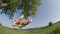 CLOSE UP LOW ANGLE: Unrecognizable young couple on date swaying on wooden swing.