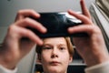 Close-up low-angle view of of Caucasian boy playing video game on mobile phone sitting at desk at home near window Royalty Free Stock Photo